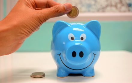 A hand putting coins into a piggy bank