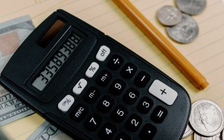 Image of a calculator, pencil and coins