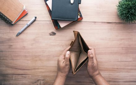 A person open an empty wallet at a table